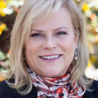 Kim Hoffmans, woman with blond hair smiling and wearing a red and white scarf